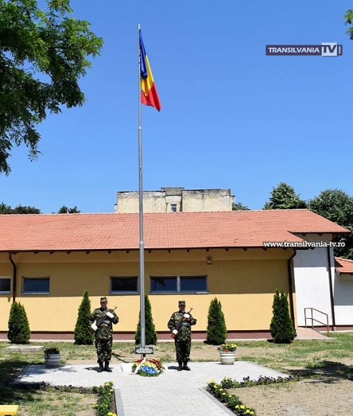 Catarg cu drapel ridicat de militari și cercetași în curtea Școlii Octavian Goga